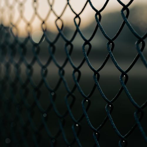 Sexton Fence installing chain-link fence panels at dusk, securing property perimeter